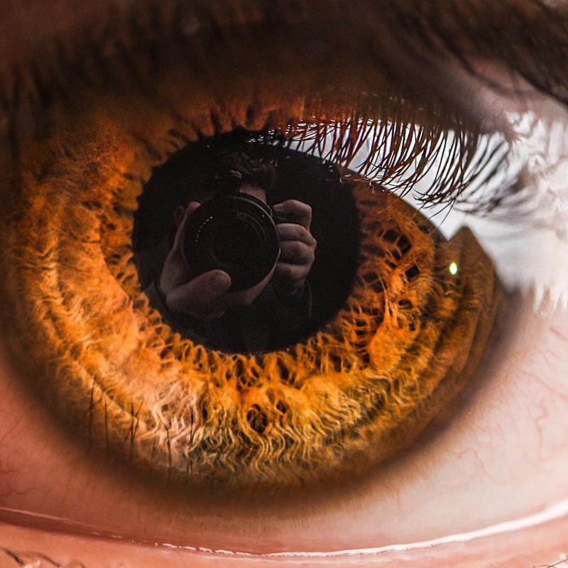 Detailed close up of an eye reflecting orange light patterns